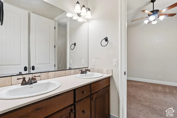 Bathroom vanity featuring dual undermount sinks, bronze-finish fixtures, and a light-toned countertop