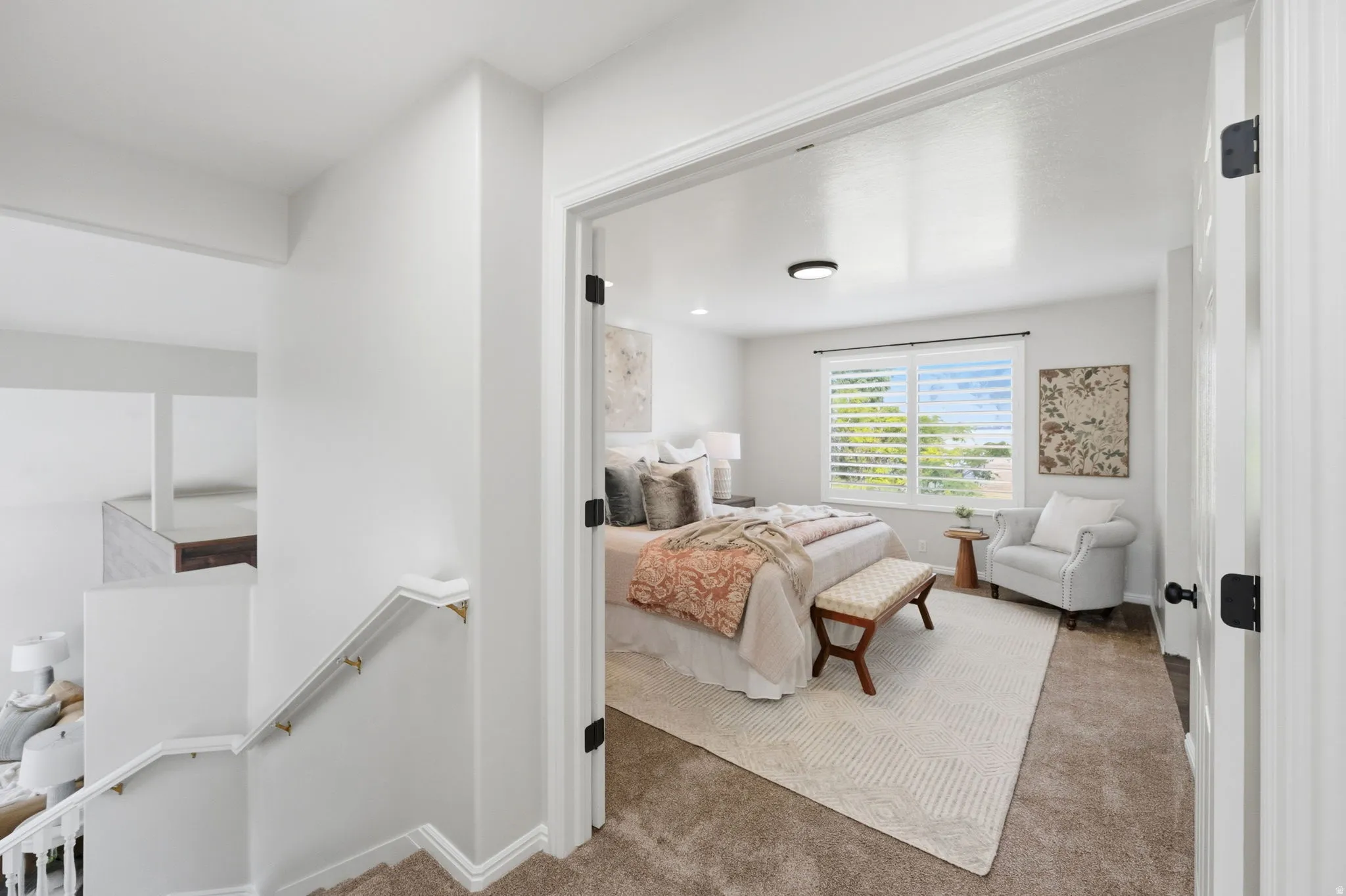Carpeted bedroom featuring a large window with plantation shutters, a contemporary ceiling light fixture, and a solid core door with black hardware