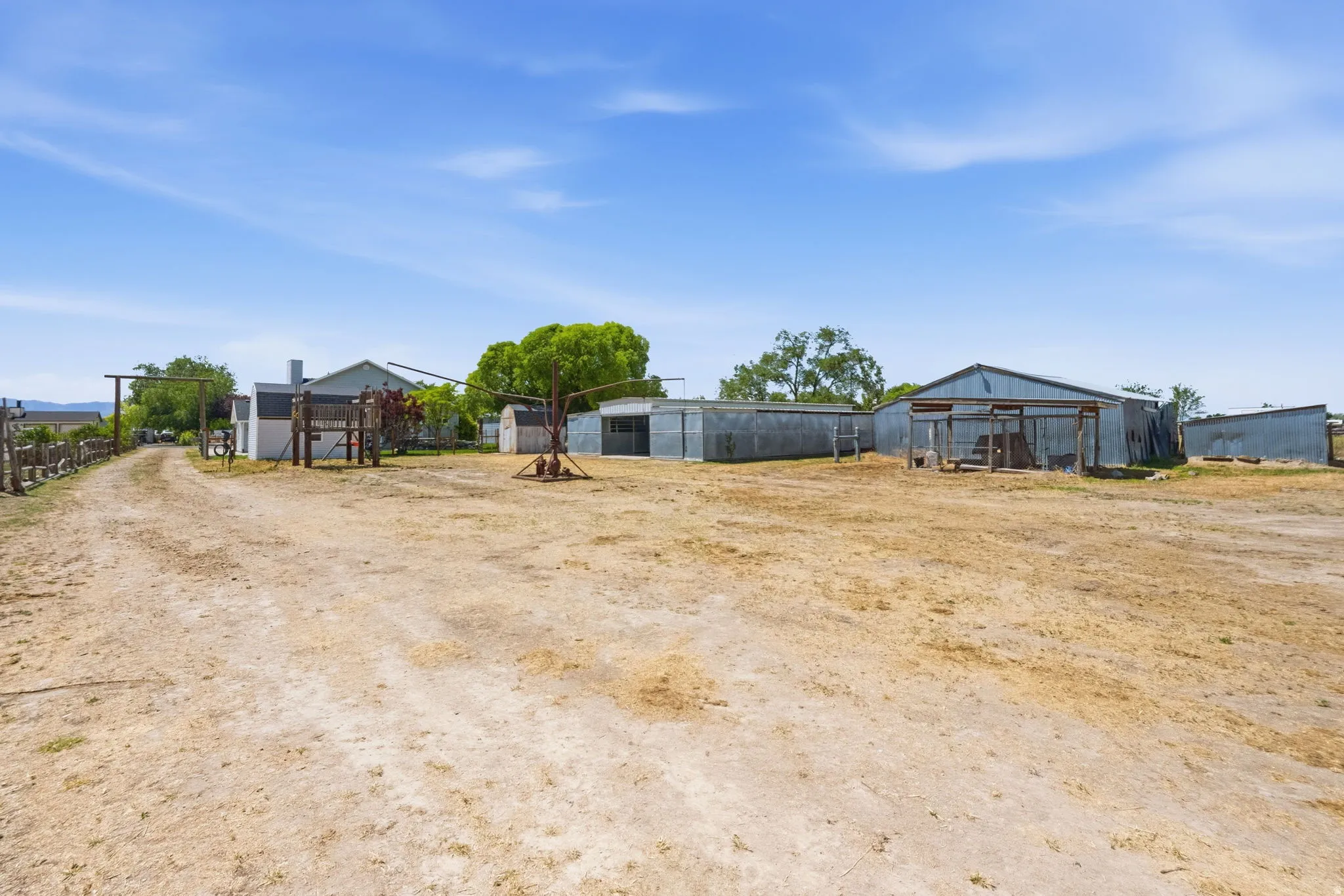 Expansive rural property featuring multiple outbuildings, a gravel driveway, and mature landscaping