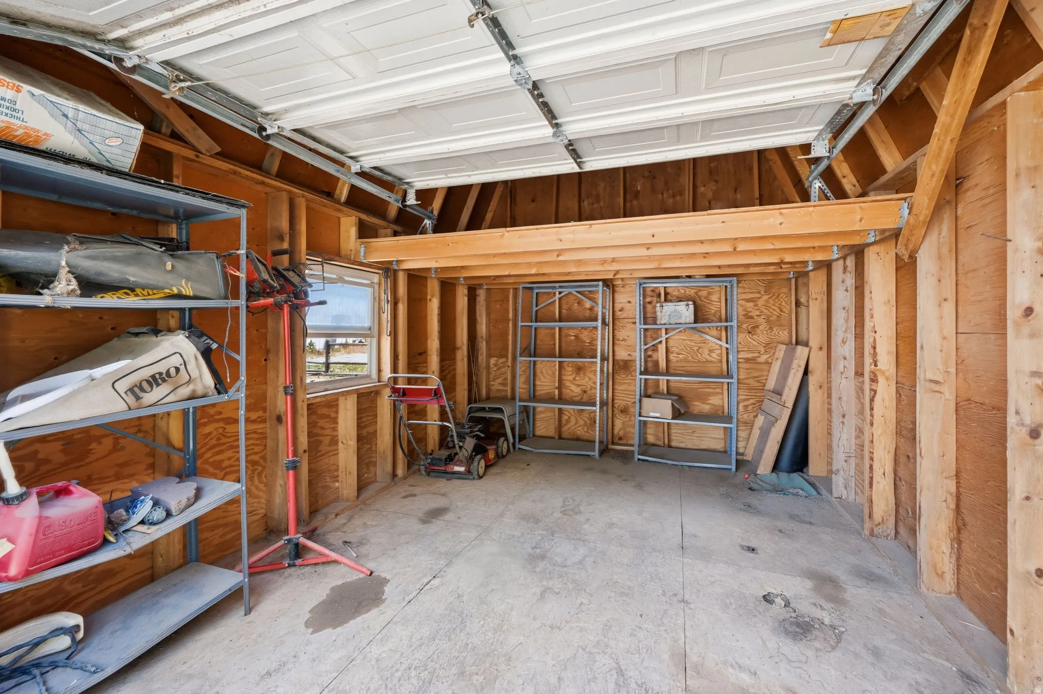 Garage interior featuring a concrete floor and exposed wood framing
