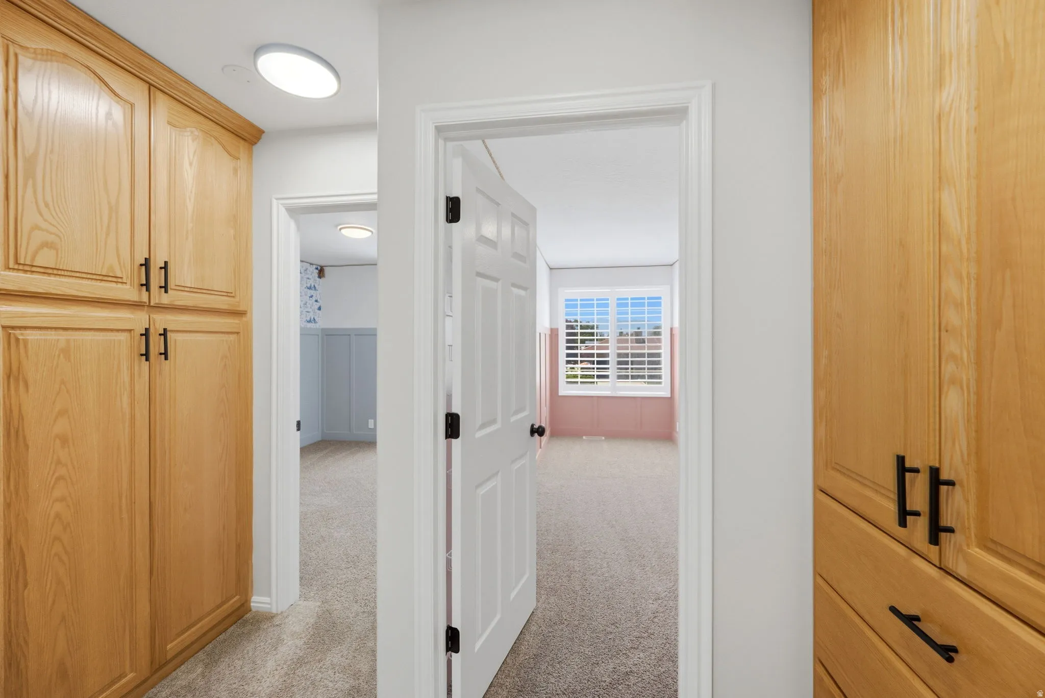 Hallway featuring built-in wood cabinetry with dark hardware and carpeted flooring