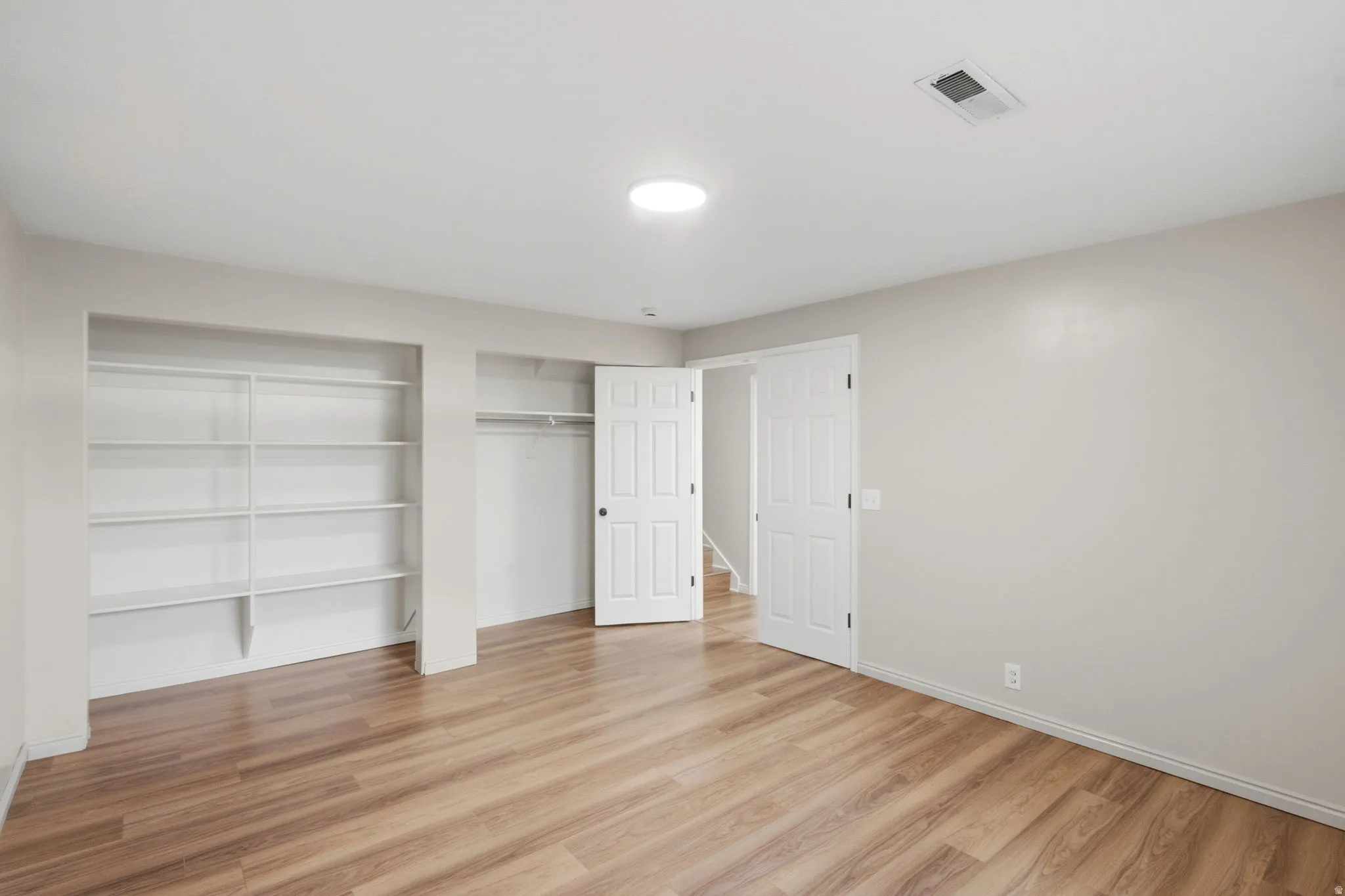Spacious room featuring wood-finish flooring and light-toned walls