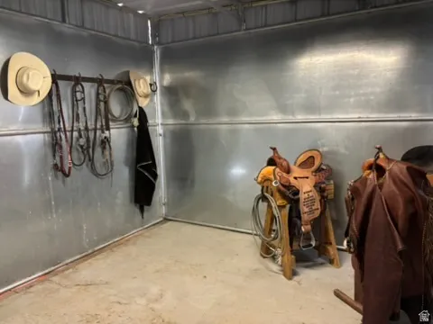 Utility space featuring corrugated metal walls, concrete flooring, and built-in wall hooks