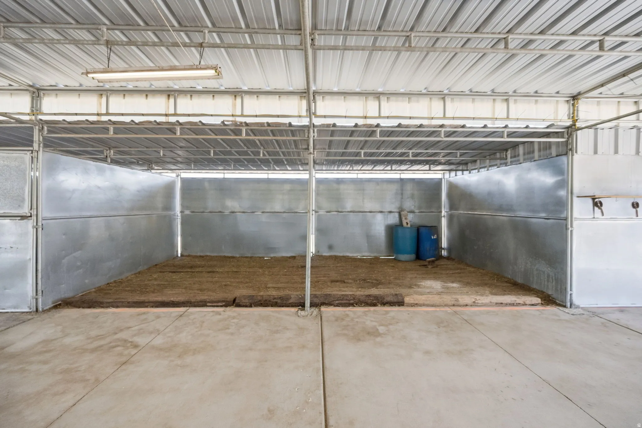 Metal framed barn structure with a corrugated metal roof and concrete flooring