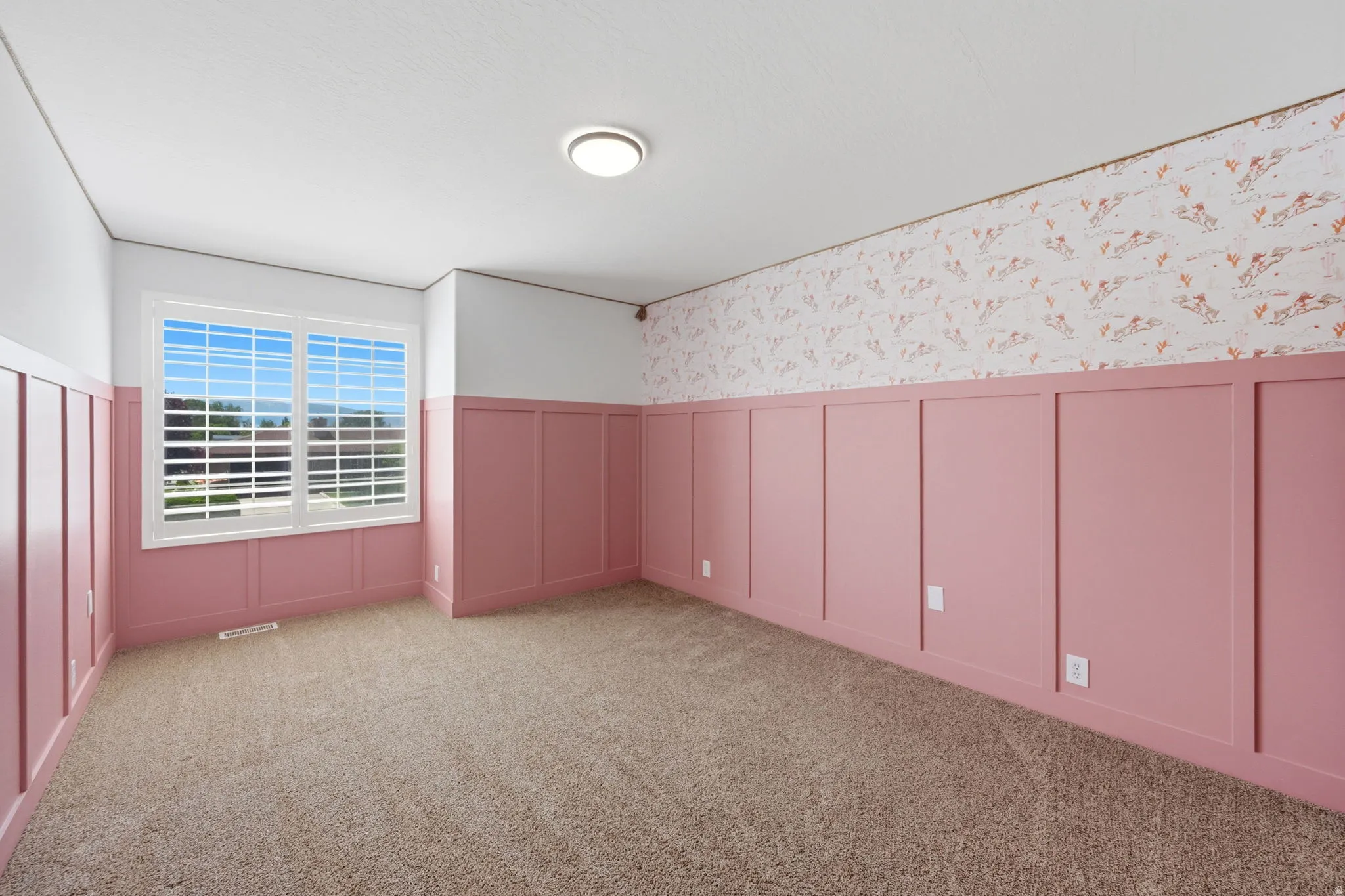 Interior room featuring pink wainscoting with white trim, complementing a patterned upper wall
