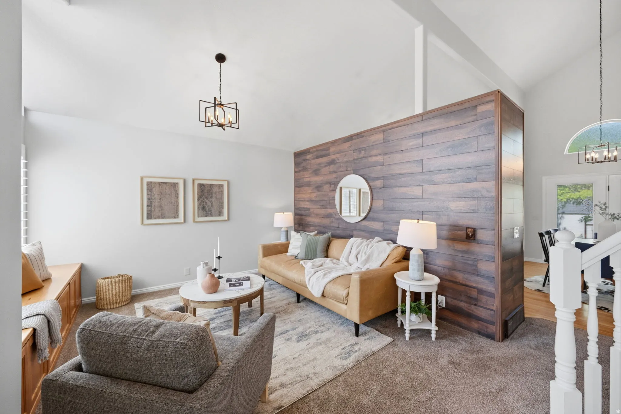 Spacious living area featuring a vaulted ceiling and a wood-panel accent wall