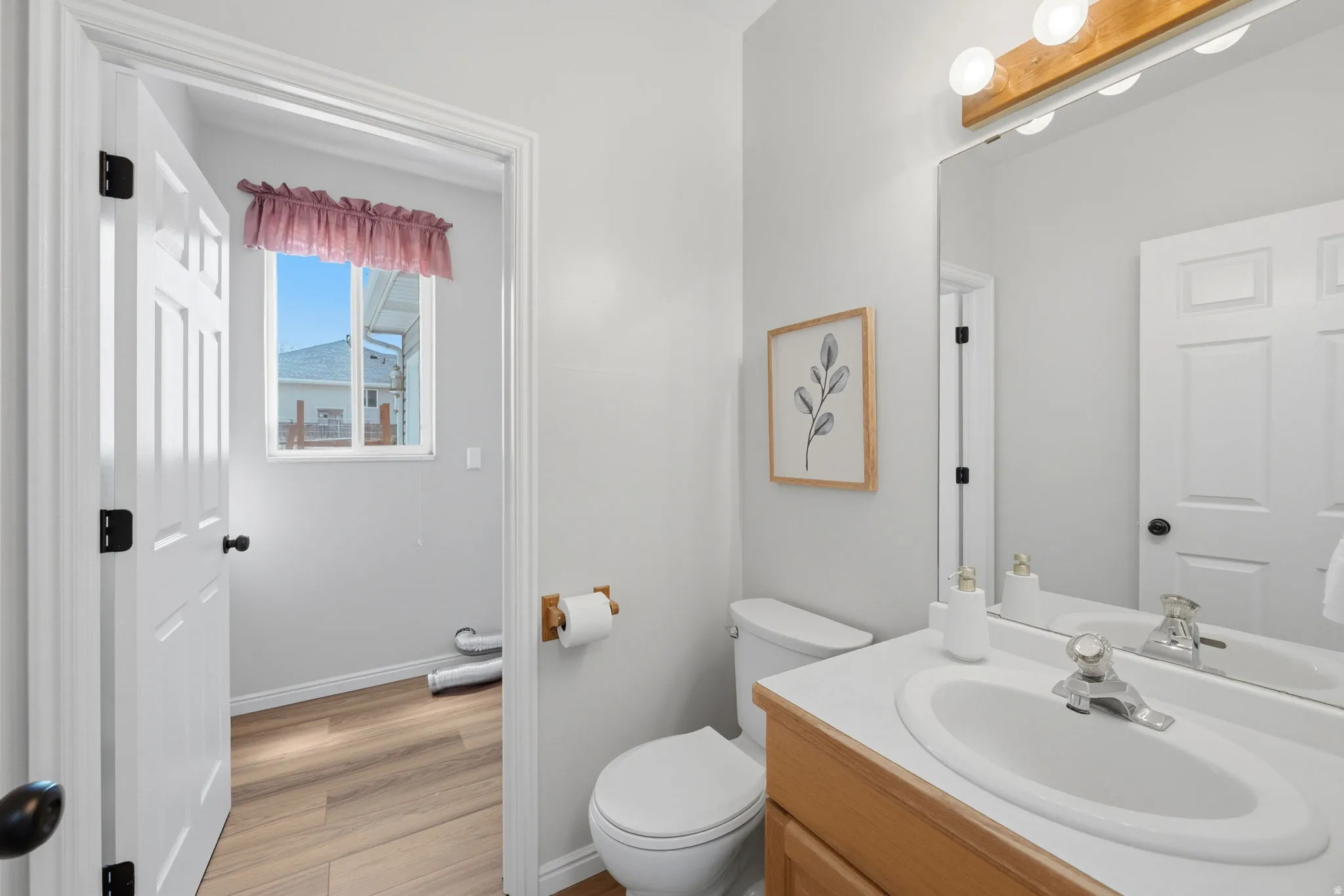 Bathroom featuring a single vanity with an integrated sink, wood-finish cabinetry, and a framed mirror