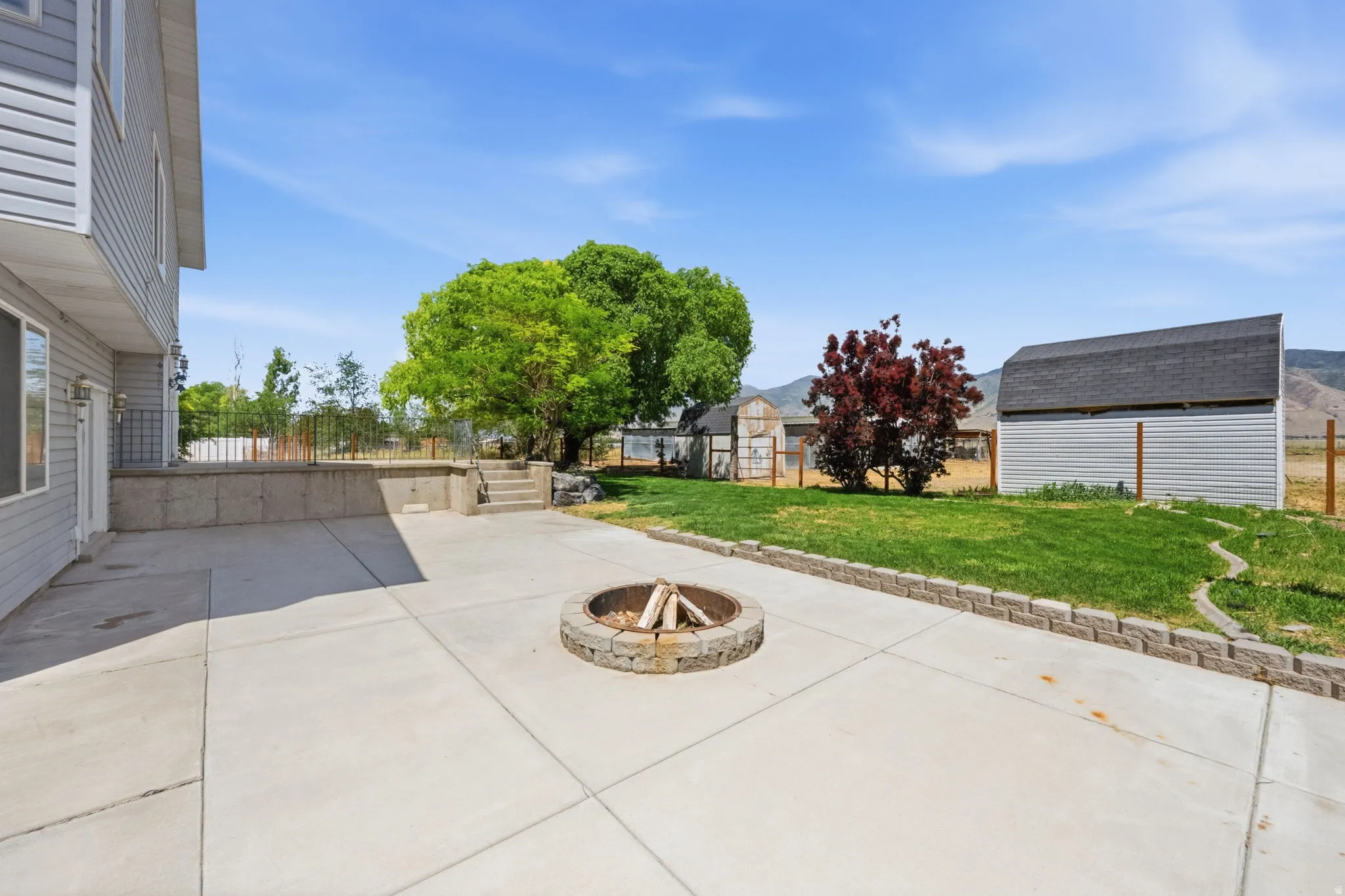 Expansive concrete patio featuring a built-in stone fire pit