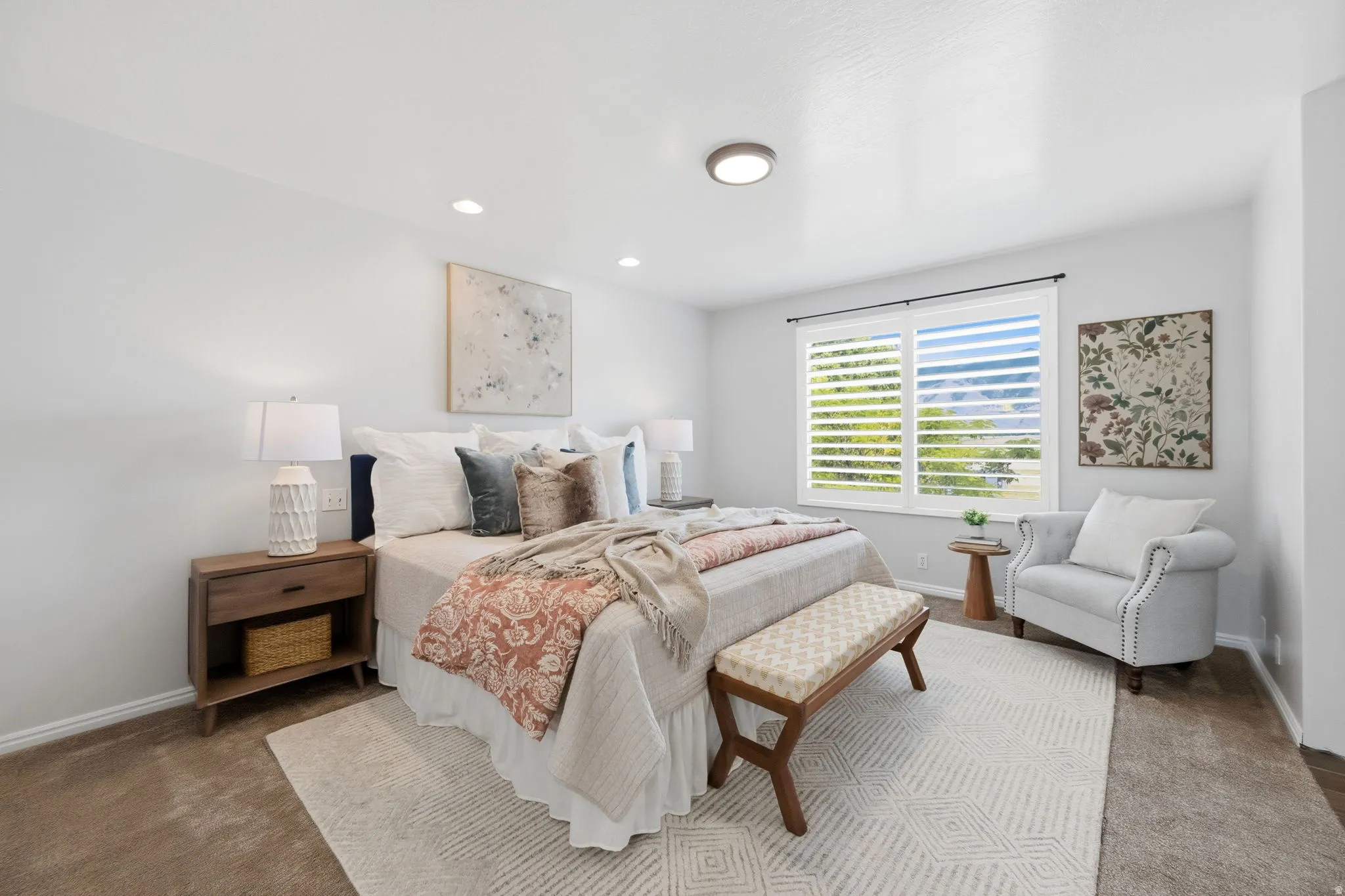 Carpeted bedroom featuring white walls and a large window with white plantation shutters