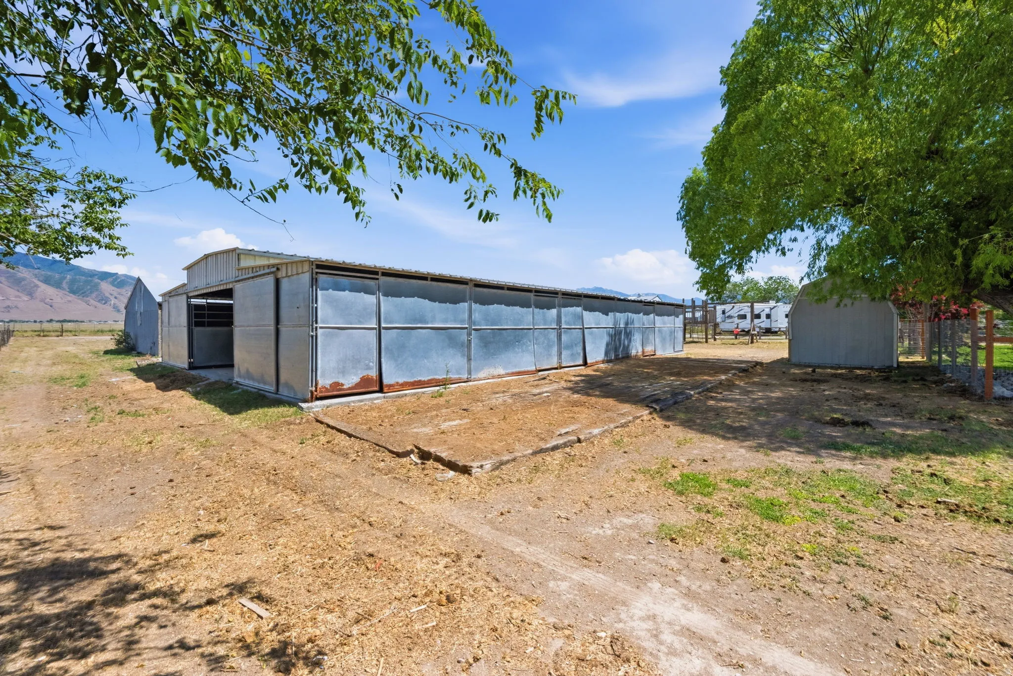 Metal-sided barn structure featuring multiple stalls and an open-front shed