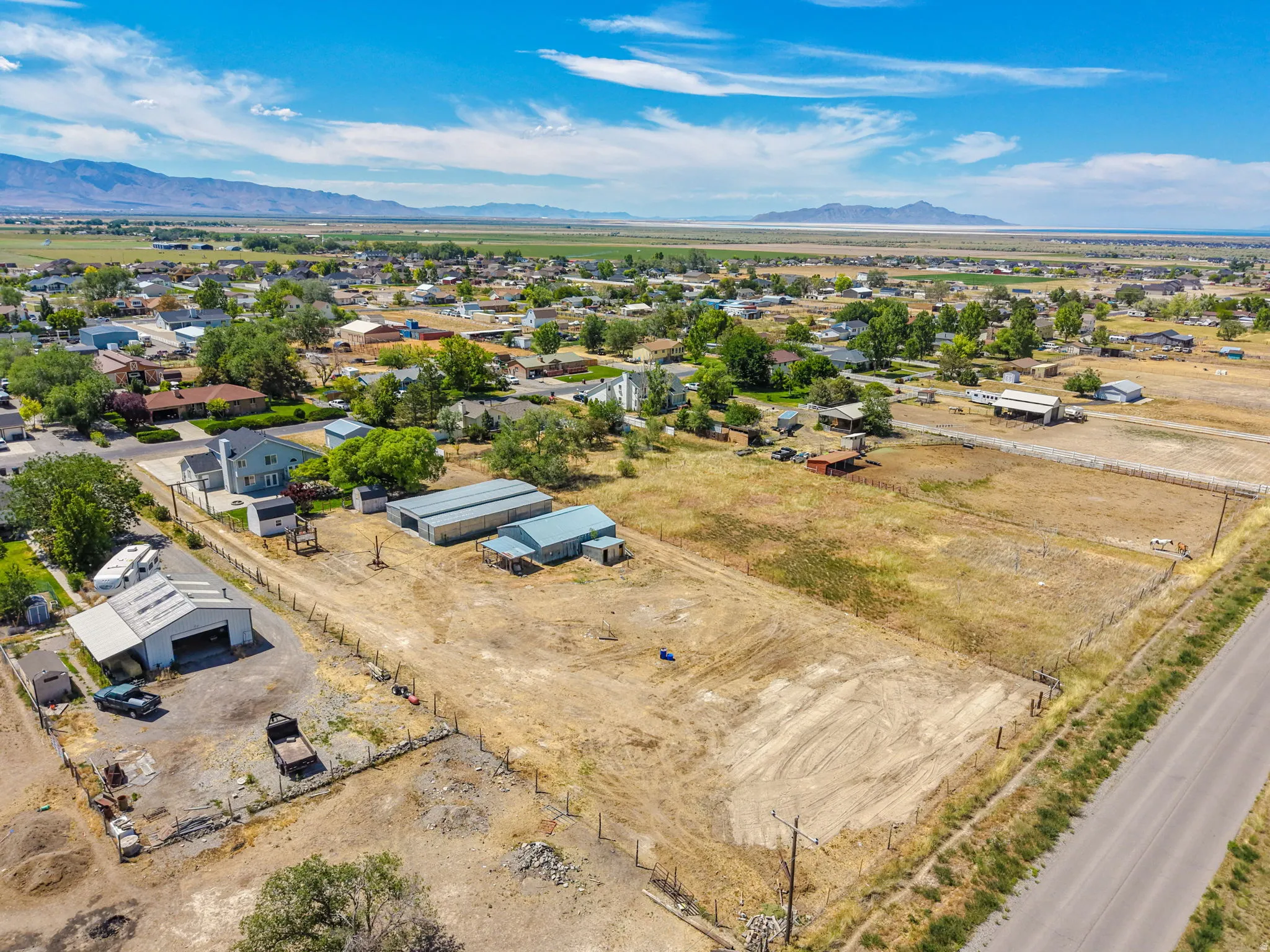 Expansive rural property featuring multiple outbuildings, open fields, and mountain range scenery