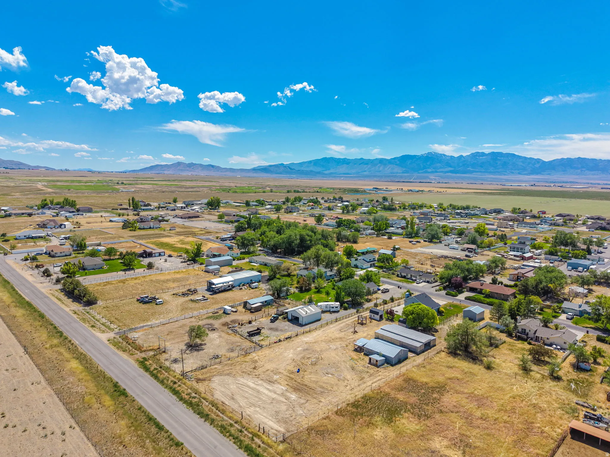 Expansive rural landscape featuring distant mountains and a clear sky with scattered clouds