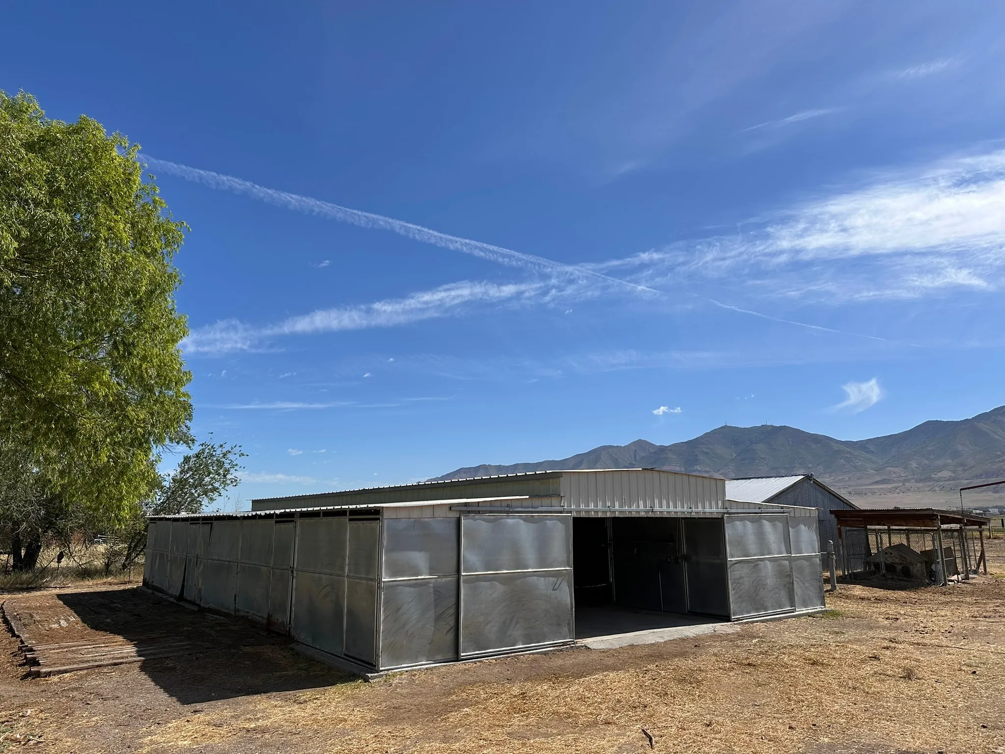 Metal barn structure featuring multiple stalls and a central open bay