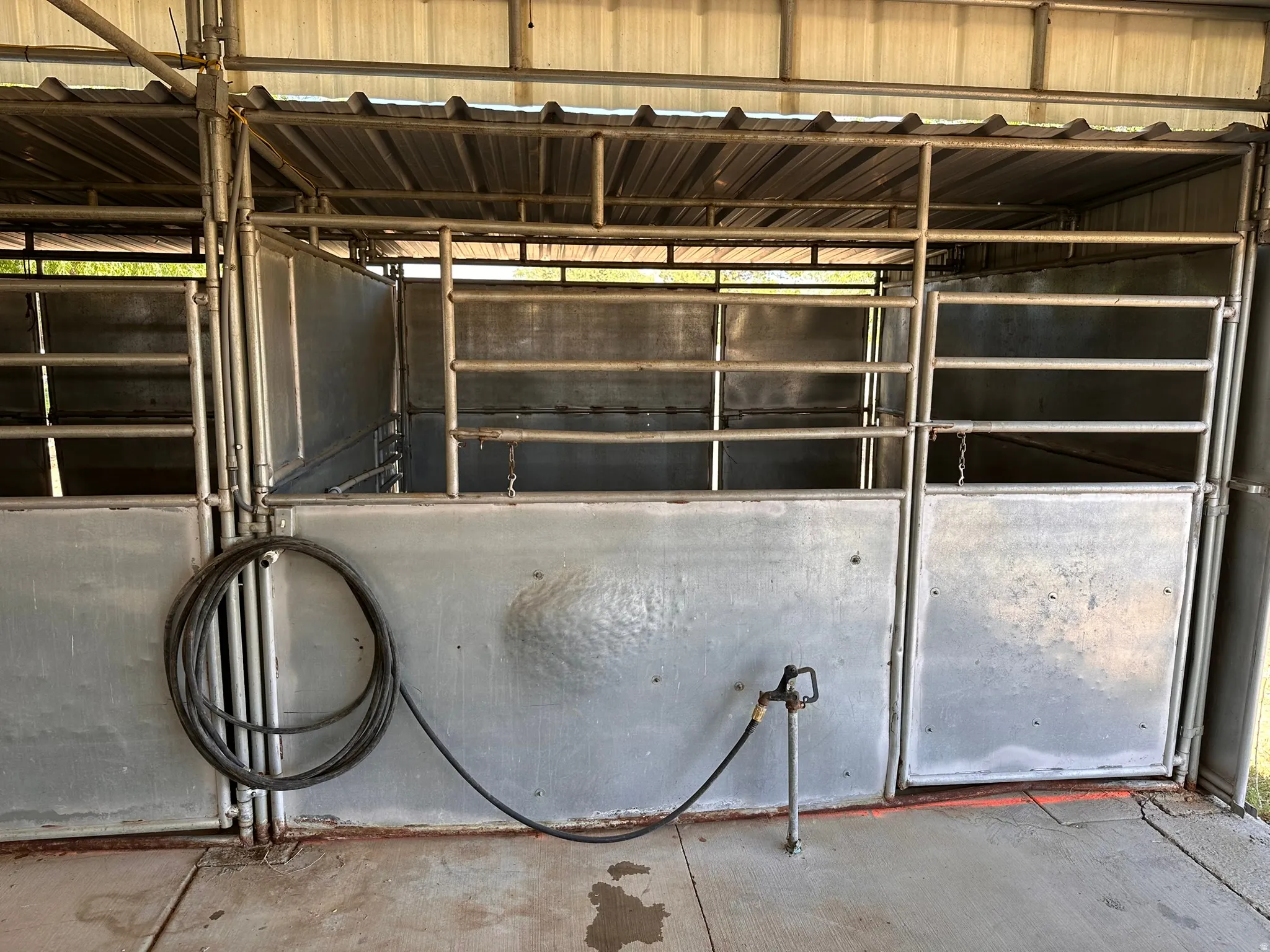 Sheltered animal stalls featuring metal construction, a corrugated metal roof, and a built-in water spigot