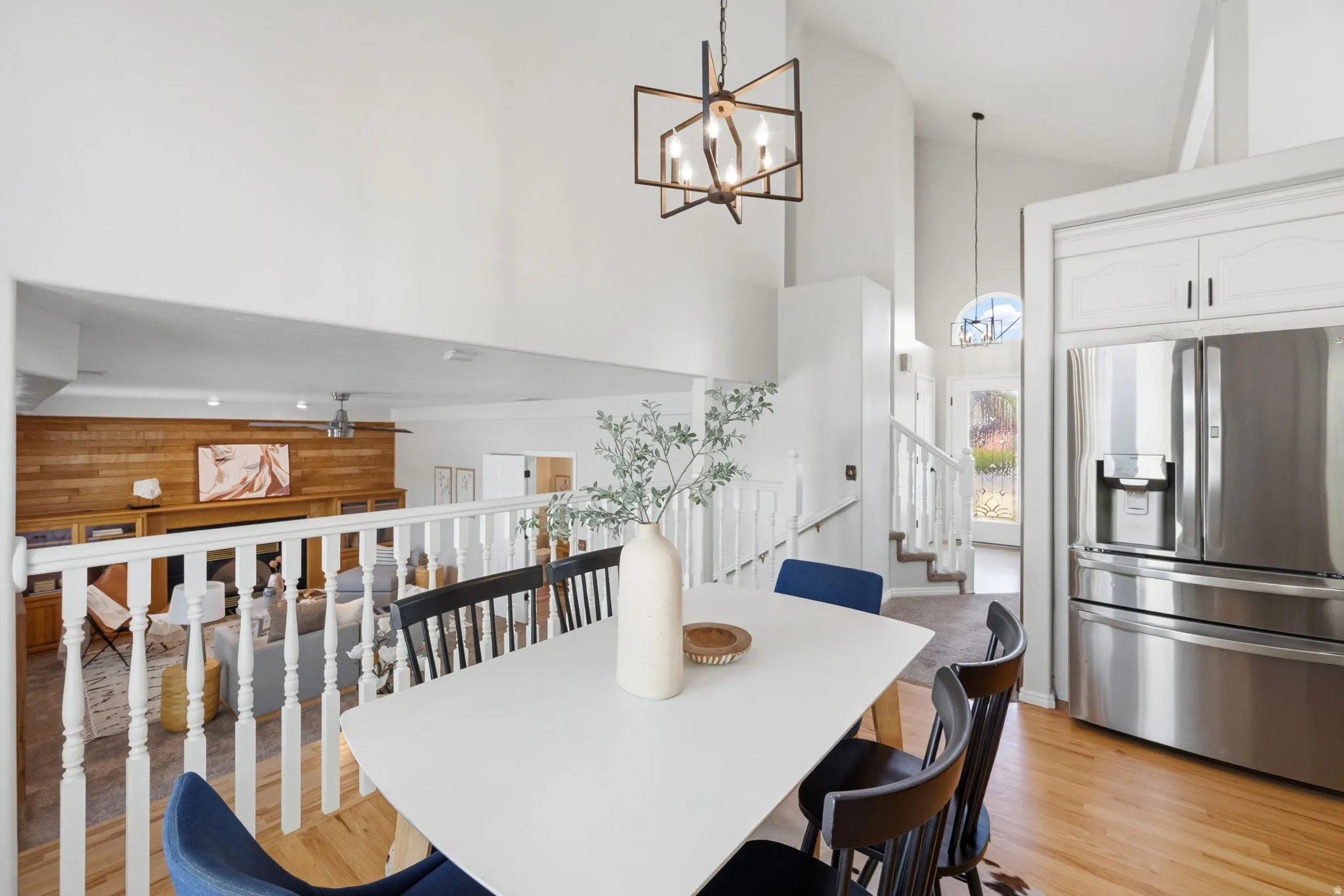 Dining area featuring a white table and chairs, hardwood-finish flooring, and a contemporary chandelier