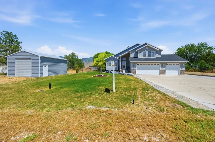 Two-story residence featuring a triple-bay garage and a separate large metal outbuilding