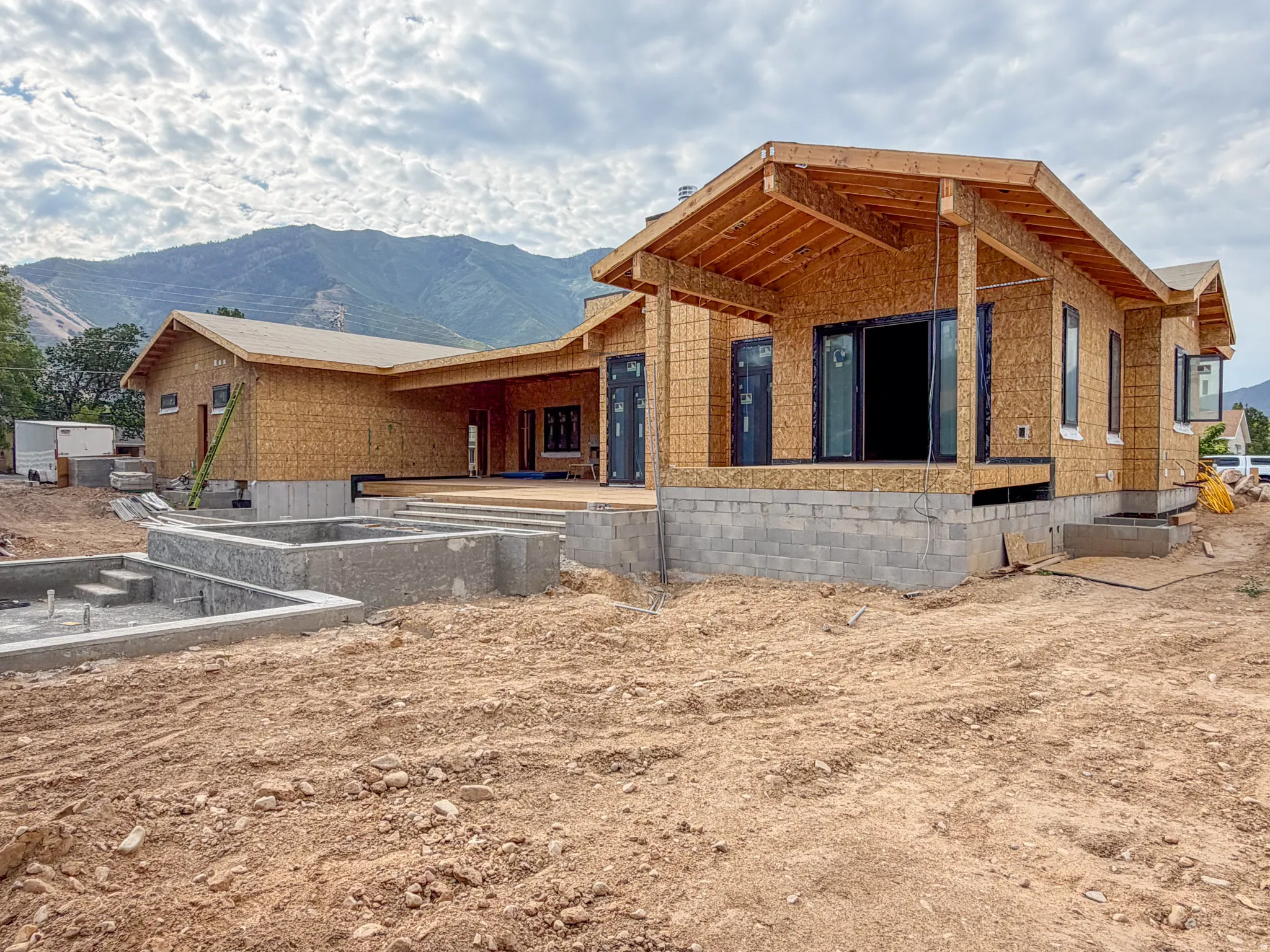New construction framing with a partial foundation and concrete forms for future hardscaping