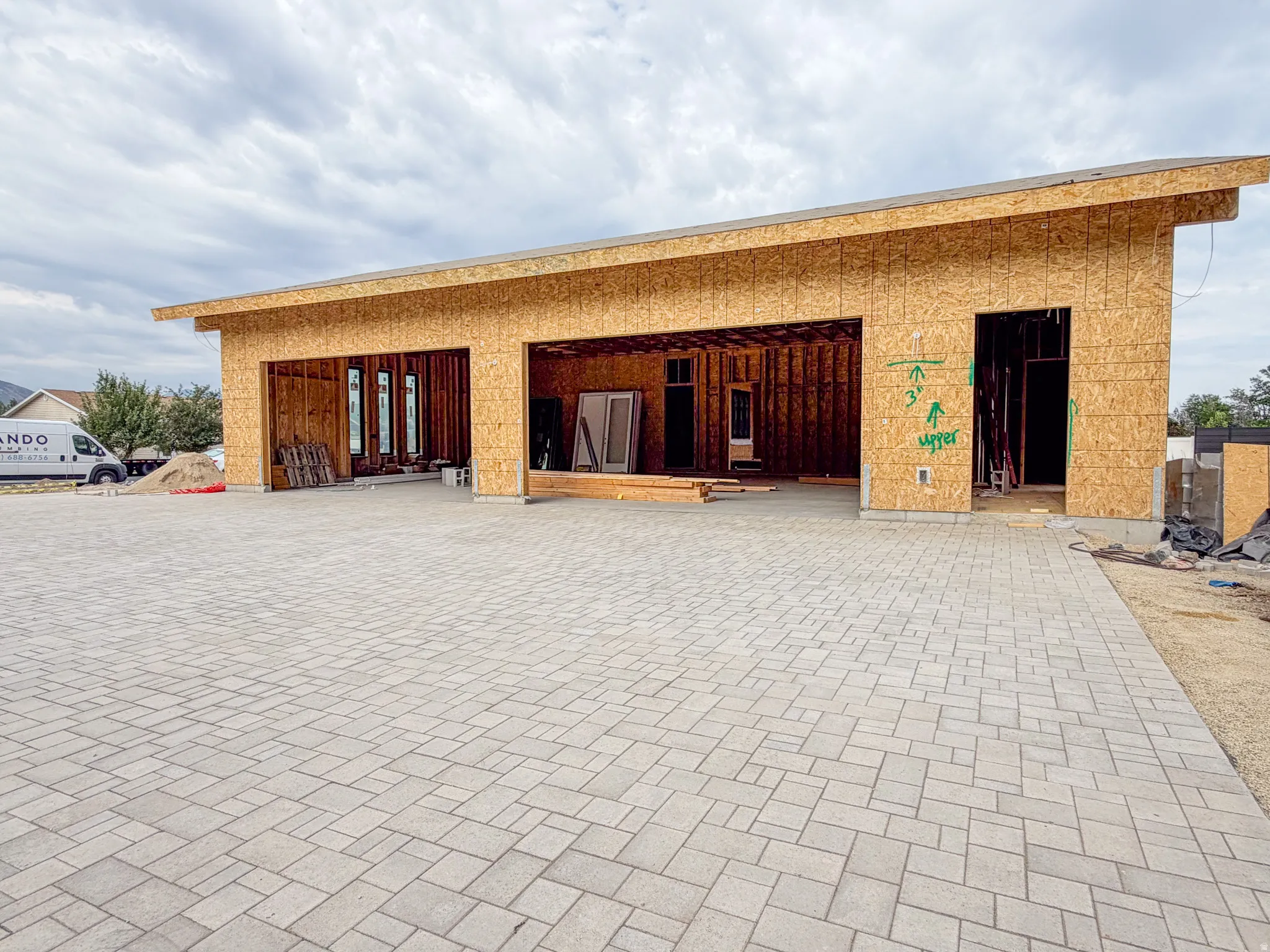 Expansive paver driveway leading to a multi-bay garage structure