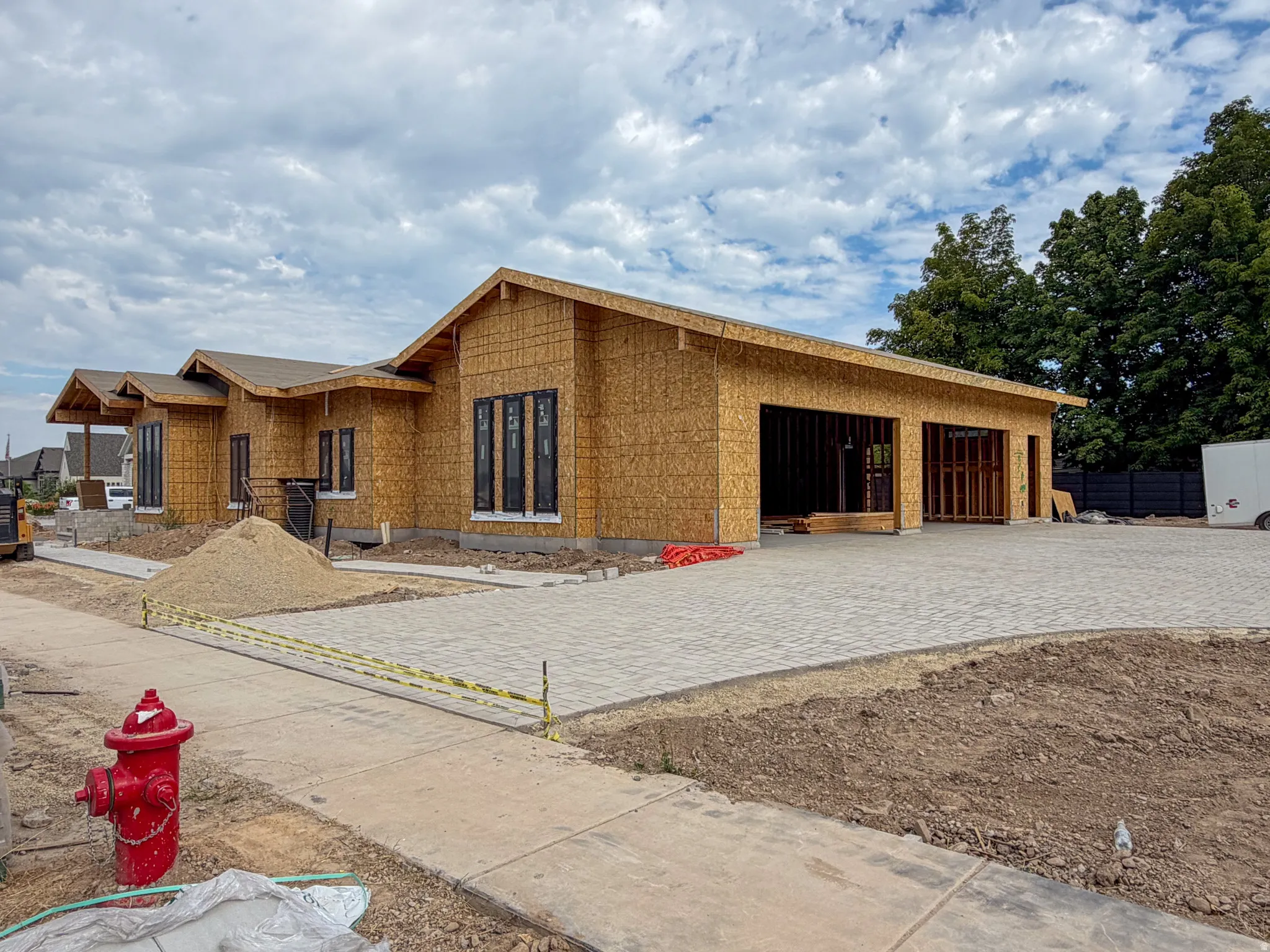 New construction featuring a multi-car garage, partial paver driveway, and contemporary black-framed windows