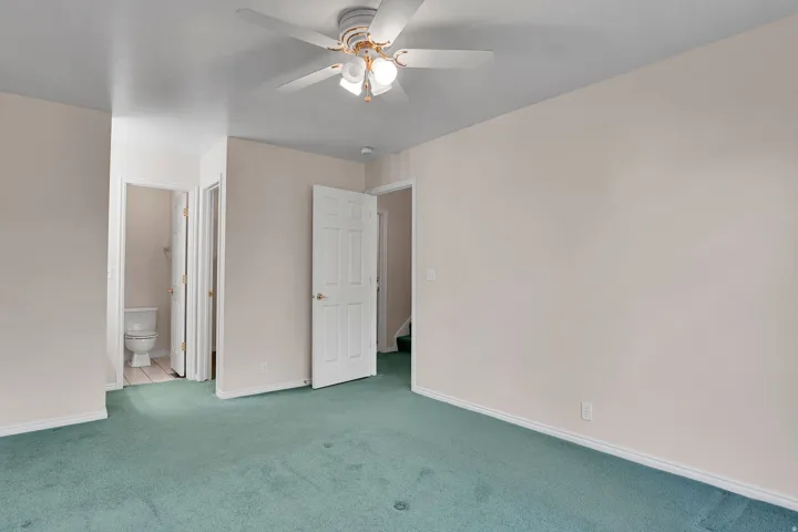 Spacious room featuring light-toned walls and green carpeting