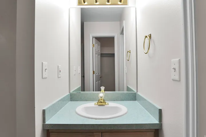 Vanity featuring an integrated oval sink, light blue countertop, and a brass-finish faucet