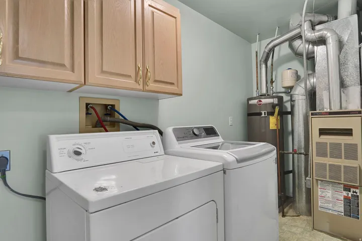 Dedicated laundry area featuring light wood-finish cabinetry, a utility sink connection, and durable flooring