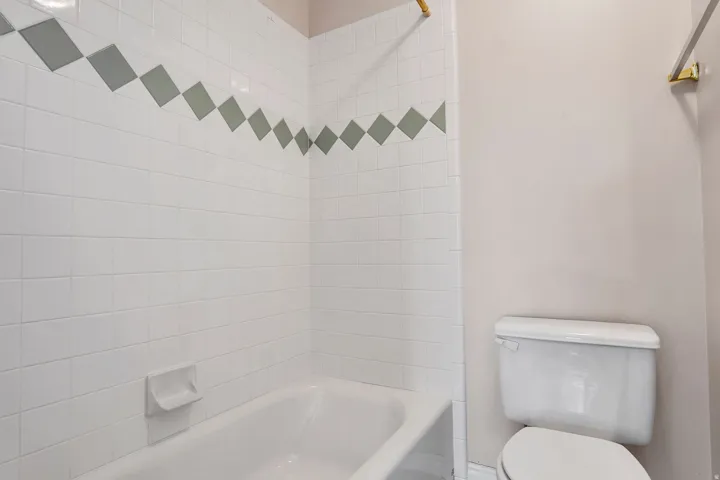 Bathroom featuring a white tiled shower with a decorative accent band