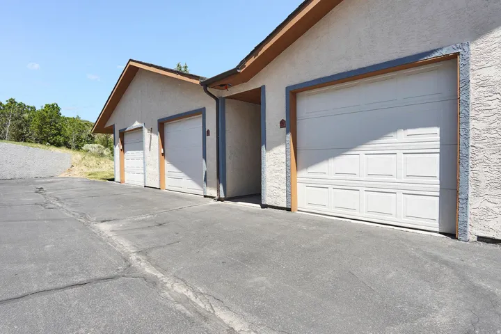 Entry and  garage bay with paneled doors, stucco exterior, and brown trim details