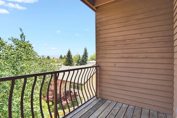 Exterior balcony featuring wood plank flooring and a decorative metal railing