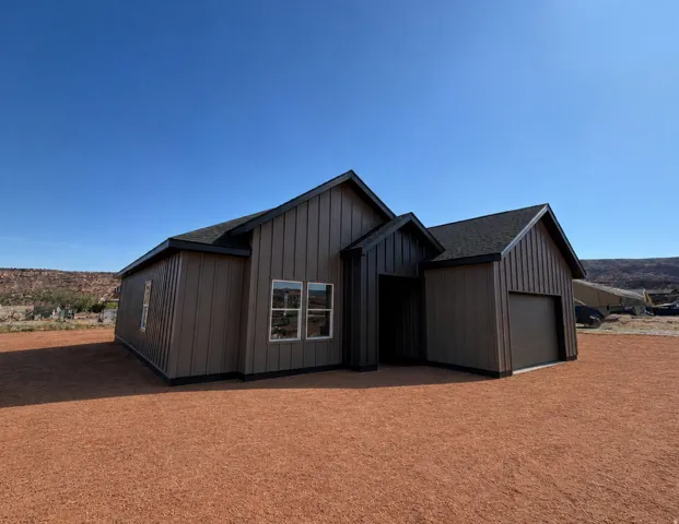 RENDERING. Modern single-story residence with vertical siding, pitched shingle roof, and attached garage.