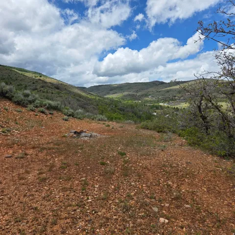 Elevated parcel featuring a sloped terrain of reddish-brown earth and scattered vegetation