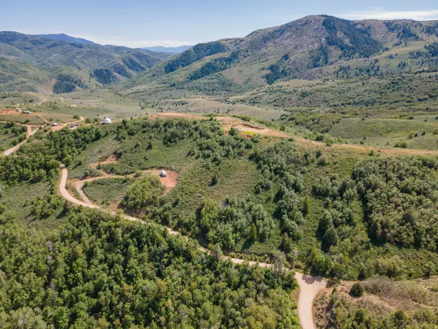 Expansive mountainous landscape featuring lush green foliage and winding unpaved roads