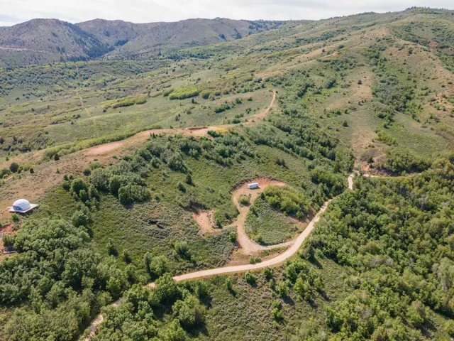 Expansive mountainous terrain featuring diverse green foliage and visible dirt roads