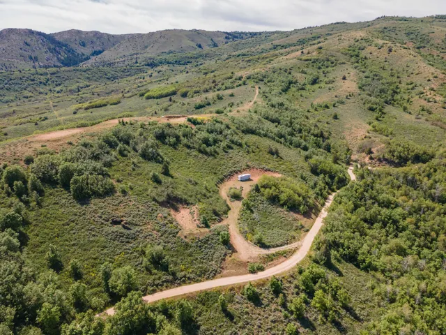 Expansive mountainous terrain featuring a winding dirt road and extensive tree coverage