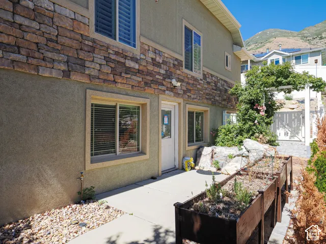 Exterior with stone veneer accent, stucco siding, and a concrete patio