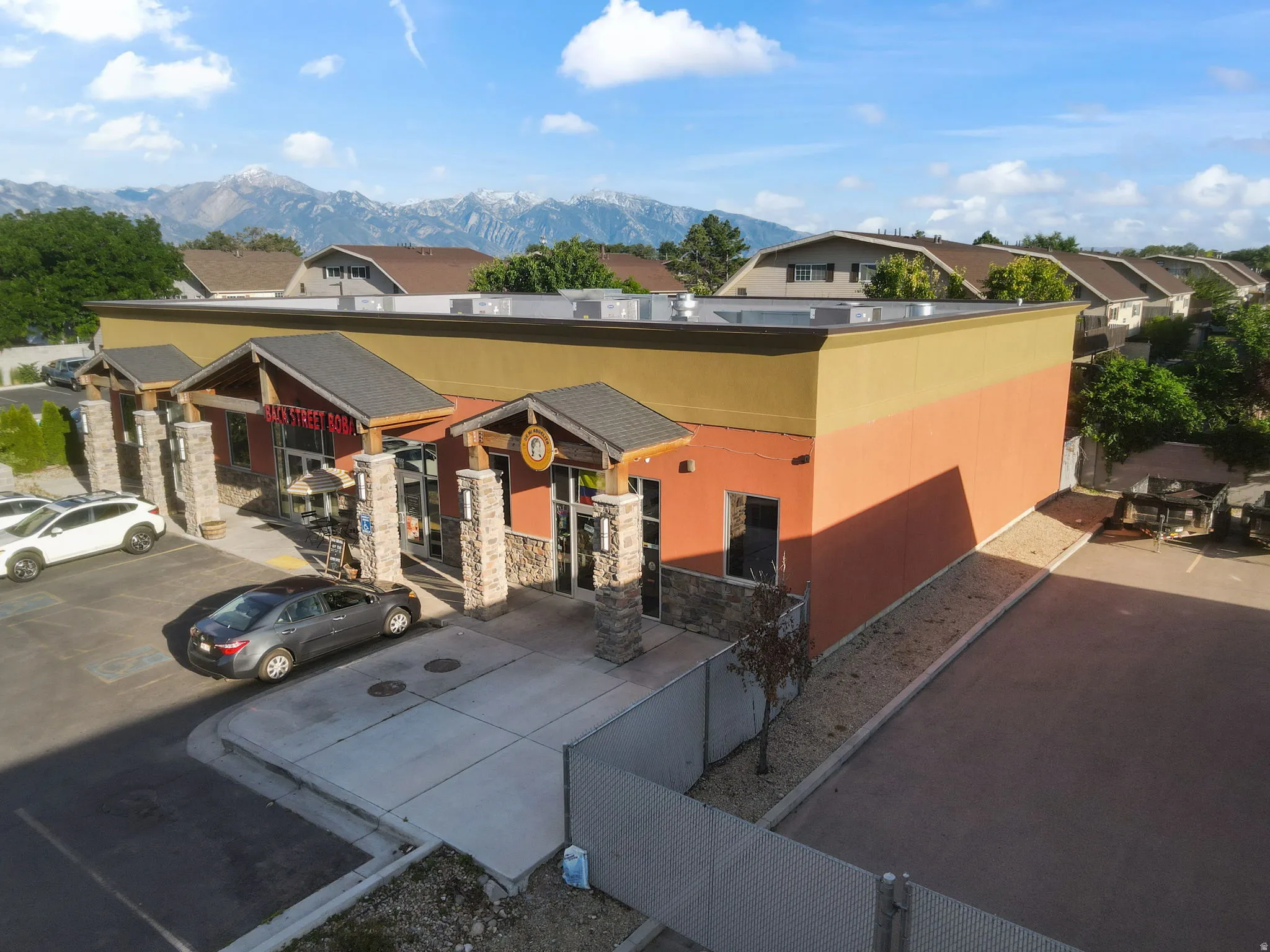 Commercial building featuring a flat roofline, stucco exterior, and prominent stone columns