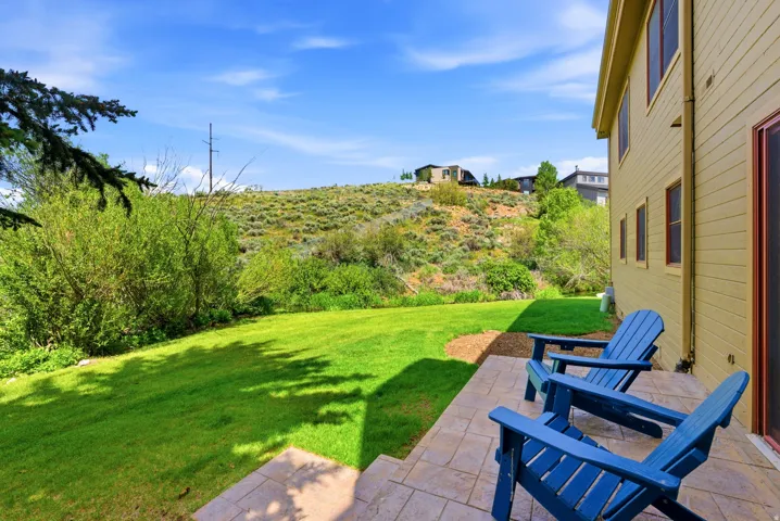 Expansive rear yard with a manicured lawn and a stone paver patio