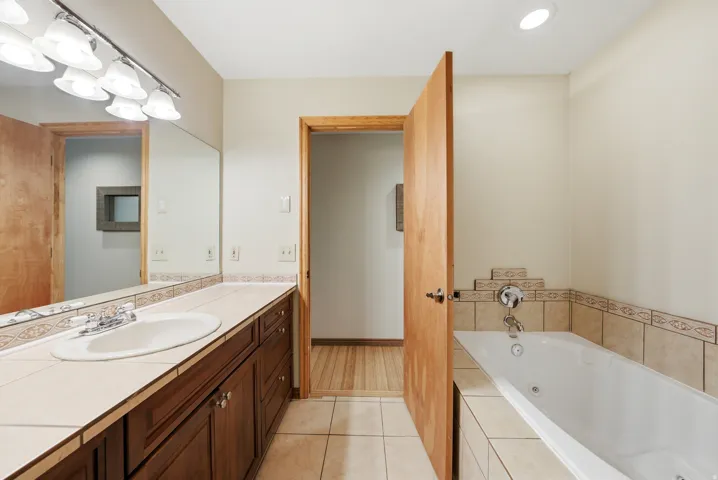 Bathroom featuring a spacious vanity with integrated sink, a large mirror, and a tiled countertop