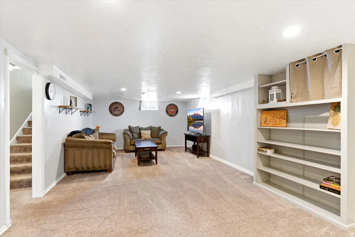 Spacious secondary living area featuring plush carpet flooring, recessed lighting, and built-in shelving