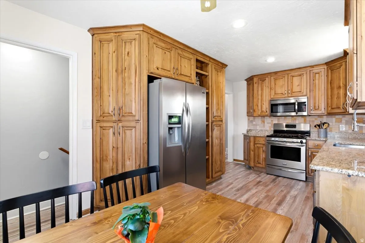 Kitchen featuring extensive wood cabinetry, stainless steel appliances, granite countertops, and a tiled backsplash