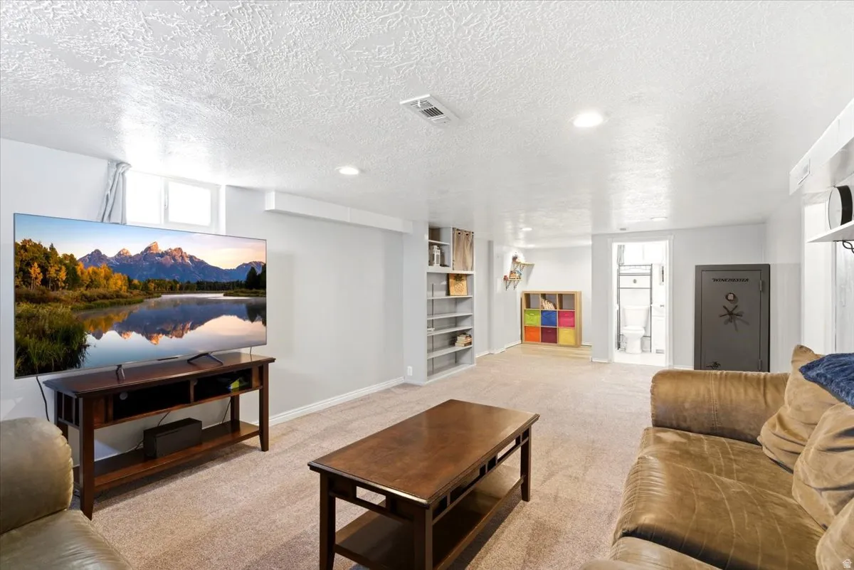 Spacious lower-level entertainment area featuring recessed lighting, a neutral carpeted floor, and painted walls