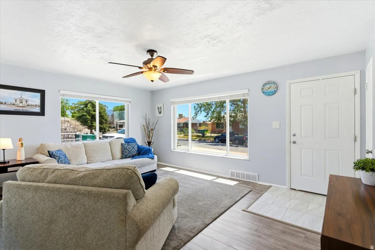 Living area featuring light blue walls and a ceiling fan with integrated lighting