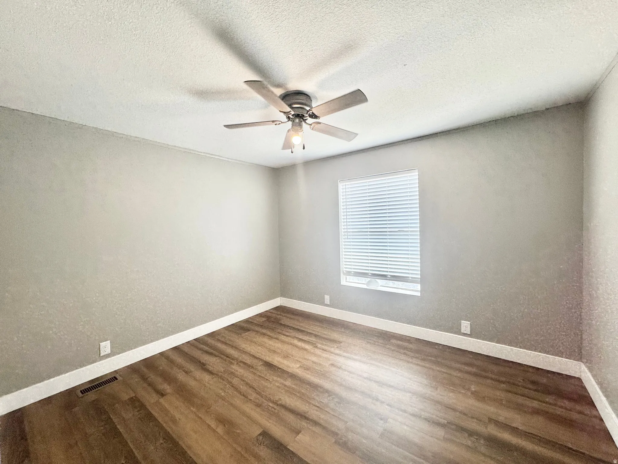 Bright interior room featuring wood-finish flooring, light grey walls, and white trim