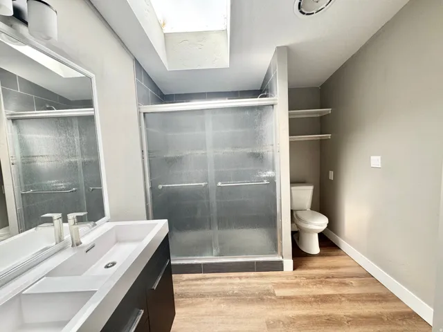 Contemporary bathroom featuring a dark wood-finish floating vanity with an integrated white sink, brushed nickel faucet, and a large mirror