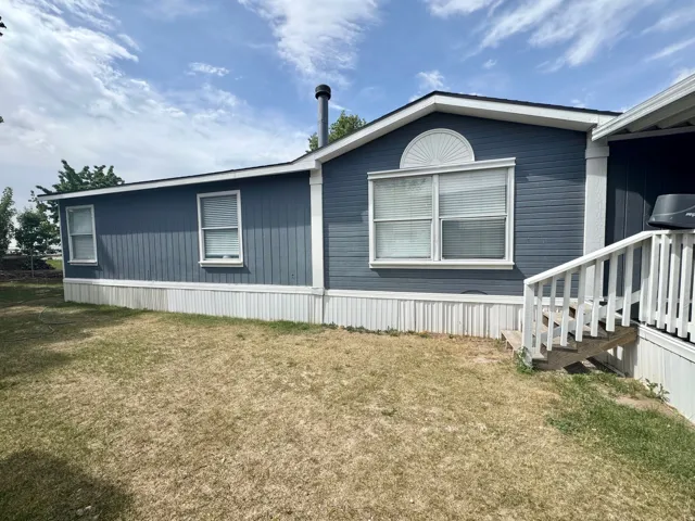 Exterior featuring blue horizontal siding, white trim, and a prominent front window with an arched detail