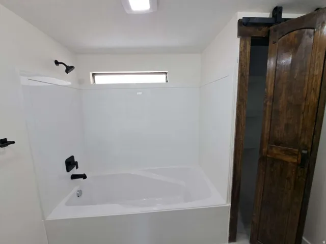 White bathtub and shower combination with matte black fixtures