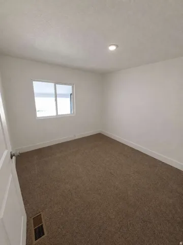 Recessed ceiling lighting, brown carpet flooring, white walls, and a white window frame