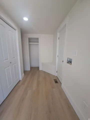 Recessed ceiling lighting, wood-finish flooring, white bi-fold doors, white interior doors, and a built-in storage niche