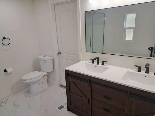 Dual vanity with integrated sinks, dark wood-finish cabinetry, and matte black fixtures