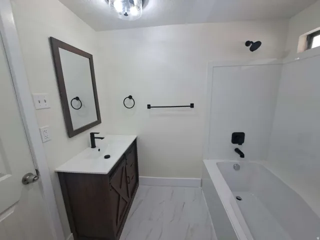 Modern bathroom featuring a dark wood-finish vanity with a white countertop and basin sink